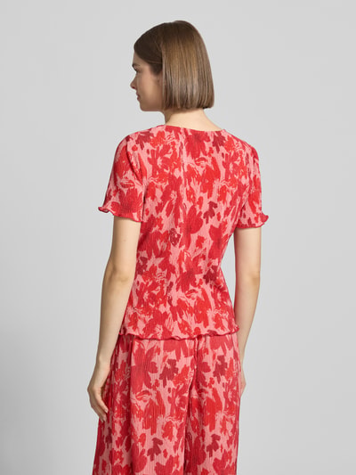 Frauenmodel trägt Slim Fit T-Shirt mit Allover-Muster Modell 'FLORA' von Pieces, florales Muster, Plissee, Ganzkörperansicht Rückansicht.