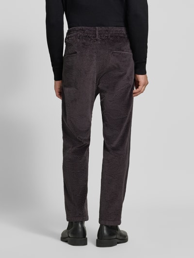Männermodel trägt Straight Fit Hose aus Baumwoll-Mix Modell 'Chasy' von DRYKORN in Cord-Optik, dunkle Farbe, Gesäßtaschen, Ganzkörperansicht Rückansicht.