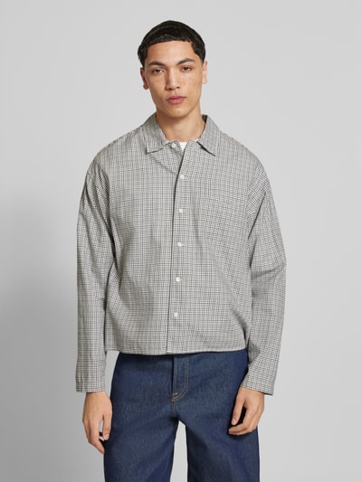 Männermodel trägt Regular Fit Freizeithemd aus Baumwolle Modell 'AUSTIN' von Jack & Jones mit feinem Karomuster, Kentkragen, Knopfleiste, Brusttasche, Farbton Grau-Weiß, weiche Textur, Ganzkörperansicht von vorne. Rückenlänge 60 cm, Schulterbreite 45 cm, Ärmellänge 57 cm.