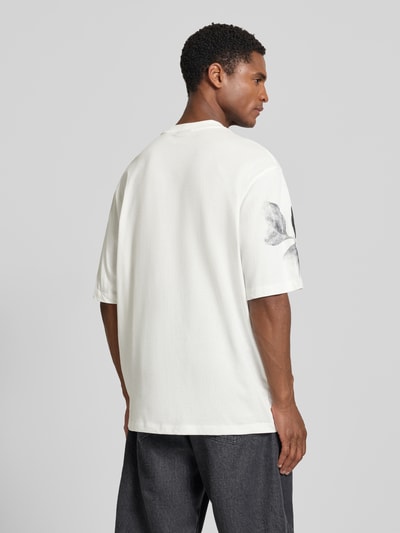 Männermodel trägt Comfort Fit T-shirt mit motiefprint van Armani Exchange in wit met all-over look, ronde hals, ruglengte maat M 76 cm, Ganzkörperansicht Rückansicht.