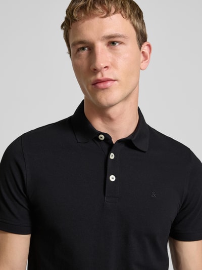 Männermodel trägt Slim Fit Poloshirt mit Viskose-Anteil Modell 'Paulos' von JACK & JONES, Baumwoll-Mix, Logo-Stitching, Nahaufnahme Oberkörper.