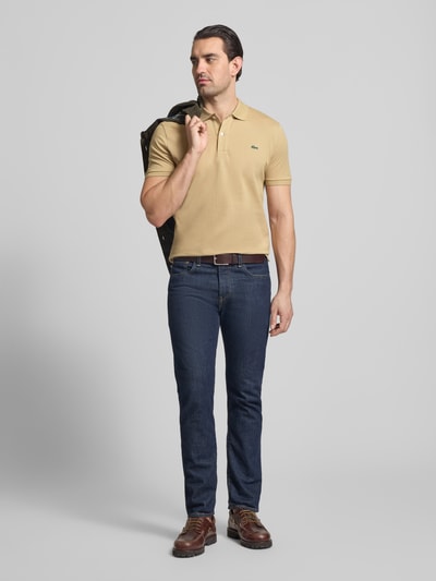 Männermodel trägt Slim Fit Poloshirt aus reiner Baumwolle von Lacoste, Optik: Unifarben, Logo-Stitching, Polokragen, kurzarm, Piqué, Ganzkörperansicht von vorne.