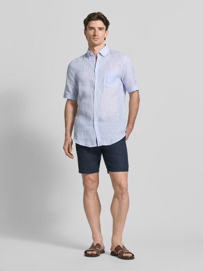 Męskienmodel nosi Regular Fit Freizeithemd aus Leinen od Christian Berg Men, niebiesko-białe paski, brustasza, krój regular fit, kołnierzyk typu button down, listwa guzikowa, len, krótki rękaw, długość tyłu w rozmiarze M: 82 cm, szerokość w rozmiarze M: 52 cm, długość rękawów w rozmiarze M: 28 cm, widok całej sylwetki z przodu.