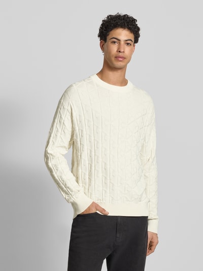 Männermodel trägt Strickpullover mit Rundhalsausschnitt Modell 'EASY' von Calvin Klein Jeans in Creme, dezentes Rautenmuster, Ganzkörperansicht von vorne, Herren Regular Fit aus reiner Baumwolle.