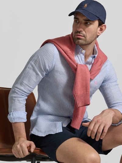 Męski model nosi Slim Fit Freizeithemd aus reinem Leinen od Polo Ralph Lauren, błękitne paski, detal z logo, kołnierzyk button down, długi rękaw, koszula casualowa z lnu, flammgarn, widok z przodu na górną część ciała.