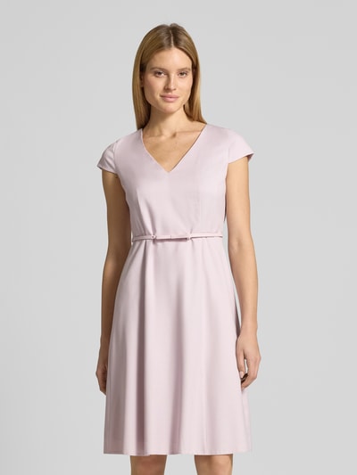 Frauenmodel trägt Knielanges Kleid mit Gürtel von Christian Berg Woman Selection in zartem Rosa, Material-Mix mit Viskose-Anteil, A-Linie, fein strukturiertem Stoff, V-Ausschnitt, Gürtel; Ganzkörperansicht von vorne.