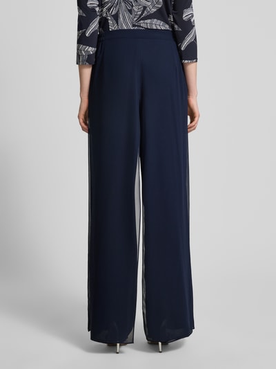 Männermodel trägt Wide Fit Stoffhose im semitransparentem Design von Vera Mont w kolorze granatowym, kopertowy styl, wszyty zamek błyskawiczny, szerokość w rozmiarze 36: 29 cm, długość wewnętrzna nogawki w rozmiarze 36: 86 cm, ganzkörperansicht rückansicht.