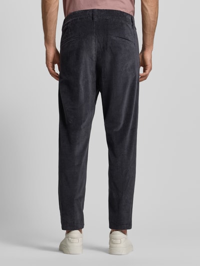 Männermodel trägt Cordhose mit französischen Eingrifftaschen von Drykorn, Baumwoll-Elasthan-Mix, gerader Schnitt, Bundfalten, Gesäßtaschen, Ganzkörperansicht Rückansicht.