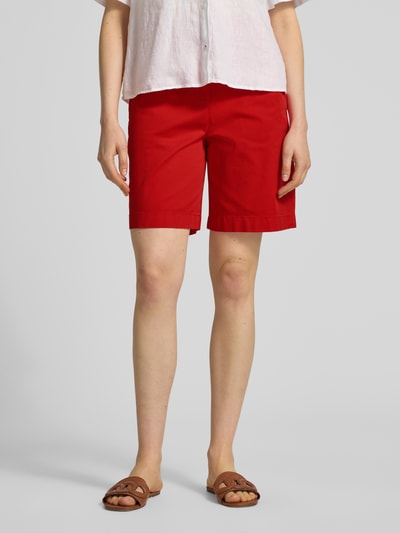 Kobiece modelka nosi Regular Fit Chino-Shorts aus Baumwoll-Lyocell-Mix von Tommy Hilfiger, efekt: jednolity kolor, krój regular fit, wyhaftowane logo, zapięcie na guzik i zamek błyskawiczny, wpuszczane kieszenie boczne, kieszenie z tyłu, materiał: mieszanka bawełny i lyocellu, Ganzkörperansicht z przodu.