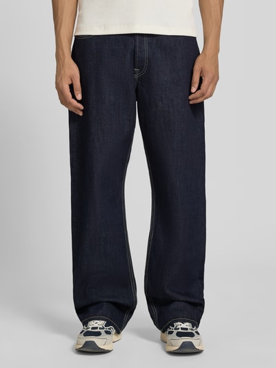 Męski model nosi Loose Straight Fit Jeans mit Eingrifftaschen Modell 'TED' von Jack & Jones z bawełny, ciemnoniebieskie, szerokość w rozmiarze 32/34: 42 cm, długość wewnętrzna nogawki w rozmiarze 32/34: 78 cm, widok całej sylwetki z przodu.