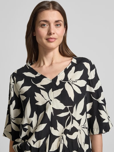 Frauenmodel trägt Relaxed Fit Blusentop aus Viskose-Mix von s.Oliver RED LABEL, floral gemustert in Schwarz und Creme, Satin-Optik, Nahaufnahme Oberkörper.