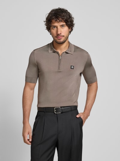 Mannenmodel draagt Regular Fit Poloshirt uit viscosemix model 'SAYFONG-4' van HUGO in effen taupe met polokraag, korte knoopsluiting, label patch en geribde boorden, jersey textuur, gehele vooraanzicht bovenlichaam.