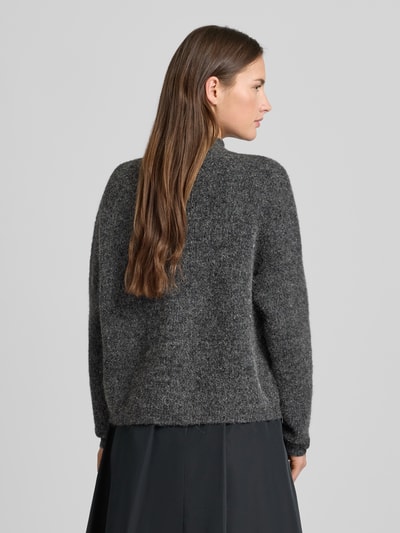 Kobiece modelka nosi kardigan rozpinany z stójką Model 'manzi' od Gestuz, krój relaxed fit, szara melanżowa tekstura, długość tyłu 54 cm, długość rękawów 52 cm, listwa guzikowa, widok całej sylwetki od tyłu.