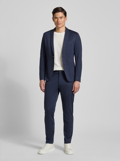 Männermodel trägt Slim Fit Jogpants aus Stretch-Jersey Modell 's.O JOGG' von s.Oliver BLACK LABEL in Dunkelblau, Ganzkörperansicht von vorne.