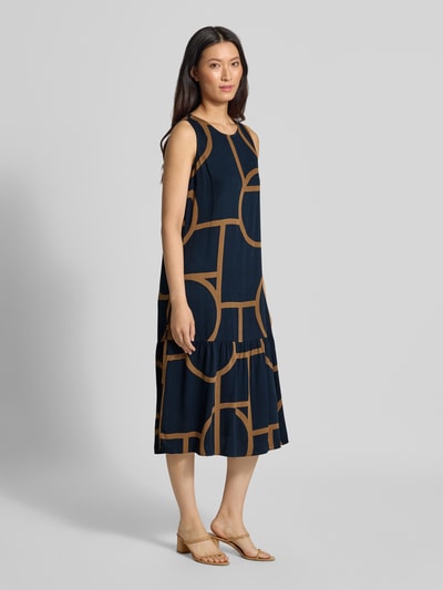 Modelka nosi Ausgestelltes Freizeitkleid aus reiner Viskose Modell 'Wicy atelier' od OPUS, granatowy z brązowym geometrycznym wzorem, sukienki casualowe, pełny widok z przodu.