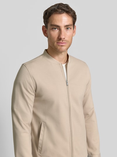 Männermodel trägt Slim Fit Sweatjacke mit Stehkragen van Lindbergh, Materiaalmix met stretch, beige kleur, steekzakken, Nahaufnahme Oberkörper.