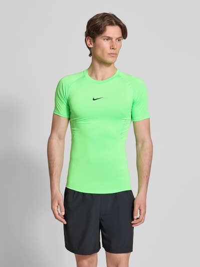 Männermodel trägt Herren T-Shirt mit Logo-Print und Rundhalsausschnitt von NIKE TRAINING, Slim-Fit, Raglanärmel, Ganzkörperansicht von vorne.