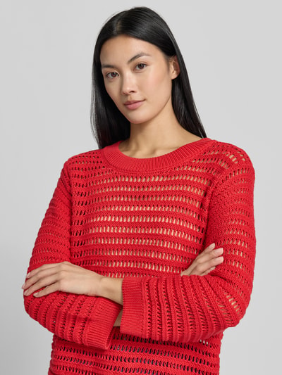 Vrouwenmodel draagt Oversized Pullover in semitransparentem Design Modell 'Ajour' van monari in rood met ajourpatroon, puur katoen, tricotlook, ruglengte bij maat 36: 54 cm, mouwlengte bij maat 36: 49 cm, detailopname bovenlichaam