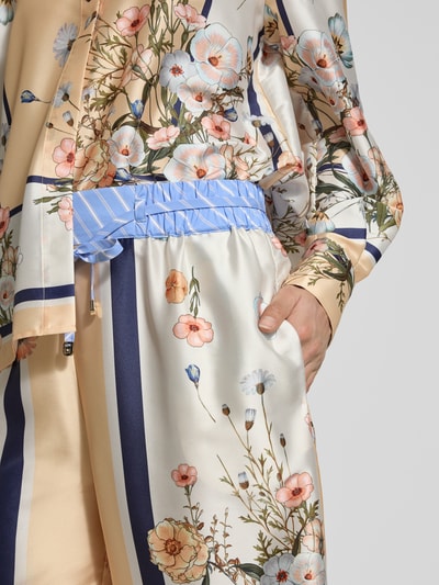Frauenmodel trägt Wide Fit Stoffhose aus Satin von Liu Jo White mit floraler Allover-Print, elastischem Bund und Tunnelzug, Nahaufnahme Oberkörper.