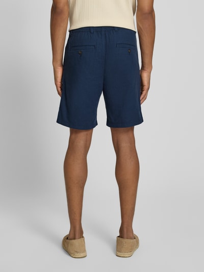 Männermodel trägt Regular Fit Chinoshorts aus Baumwoll-Leinen-Mix Modell 'BRODY' von SELECTED HOMME in Dunkelblau, Ganzkörperansicht Rückansicht.