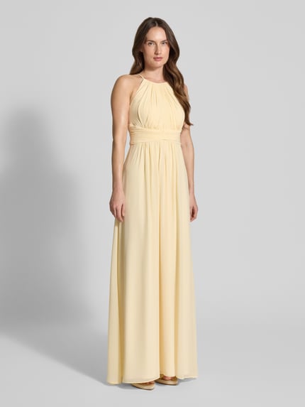 Frauenmodel trägt Abendkleid mit Raffungen von Jake*s Cocktail in zartgelber Maxilänge, taillierte Passform, Rückenausschnitt, Ganzkörperansicht von vorne.