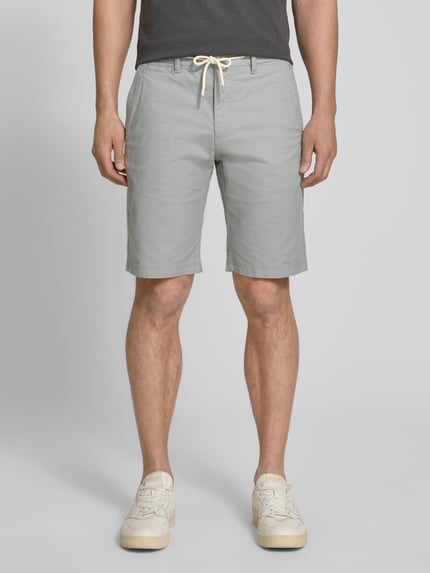 Männermodel trägt Regular Fit Chinoshorts aus Baumwoll-Mix Modell 'PHOENIX' von s.Oliver RED LABEL in Bi-Color Optik, 5-Pocket-Design, Tunnelzug, elastischer Bundabschluss, Ganzkörperansicht von vorne.