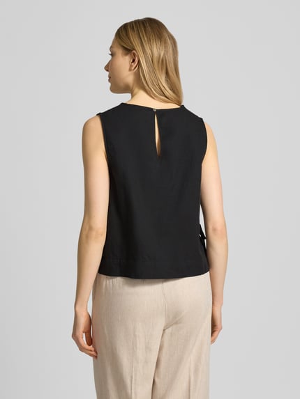 Frauenmodel trägt Blusenshirt mit seitlicher Schnürung Modell 'Svetlana' von Neo Noir, schwarze Reine Baumwolle, Lockerer-Schnitt, Rundhalsausschnitt, Rückenlänge 51 cm bei Größe 36, Ganzkörperansicht Rückansicht.