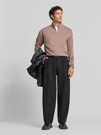 Männermodel trägt Regular Fit Troyer aus Baumwoll-Mix Modell 'Dalizip' von HUGO in Beige, kombiniert mit schwarzer Hose, Ganzkörperansicht von vorne, Herren Troyer von HUGO.