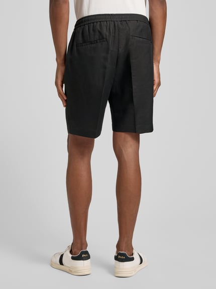 Männermodel trägt schwarze Shorts aus Leinen-Viskose-Mix Modell 'NEIL' von Antony Morato, Regular-Fit, Bügelfalten, elastischer Bund, Ganzkörperansicht Rückansicht. Herren Shorts, Bundweite bei Größe 50: 42 cm, Innenbeinlänge: 17 cm.