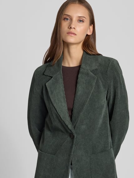 Frauenmodel trägt Regular Fit Mantel mit Reverskragen Modell 'ASTRID' von ONLY in unifarbenem, grünem Cord mit Vordertasche, Nahaufnahme Oberkörper.