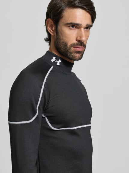 Męski model nosi Funktionsshirt mit Stehkragen und Label-Stitching od Under Armour, czarny, mieszanka materiałów z dodatkiem streczu, krój slim fit, model Cold Weather Grid, wyhaftowane logo, długość tyłu przy rozmiarze M: 73 cm, zbliżenie na górną część ciała, widok z przodu.