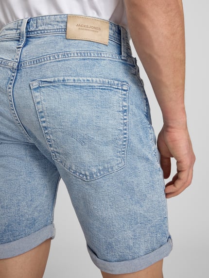 Männermodel trägt Regular Fit Jeansshorts mit Umschlag Modell 'RICK' von Jack & Jones aus Baumwoll-Elasthan-Mix, Detailaufnahme Rückansicht.