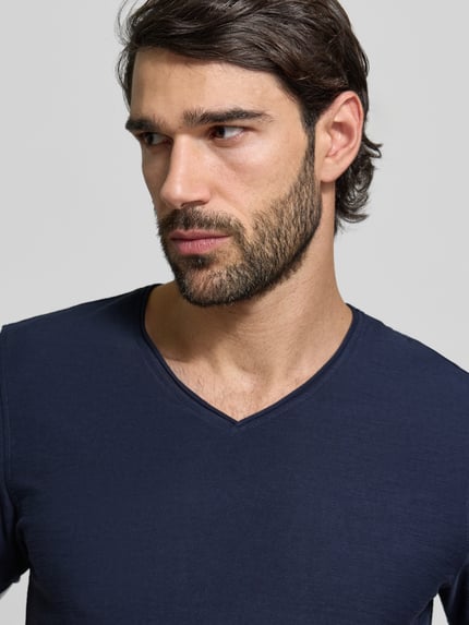 Męski model nosi T-Shirt mit geripptem Rundhalsausschnitt von MCNEAL w kolorze granatowym, krój regular fit, zbliżenie na górną część ciała. Długość tyłu w rozmiarze M: 65 cm.