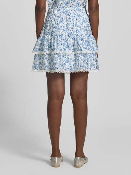 Frauenmodel trägt Ausgestellter Rock aus Viskose-Mix Modell 'BLISS' von Vero Moda mit Florales-Allover-Muster, Popeline, Mini-Länge, Elastisch, Ganzkörperansicht Rückansicht.