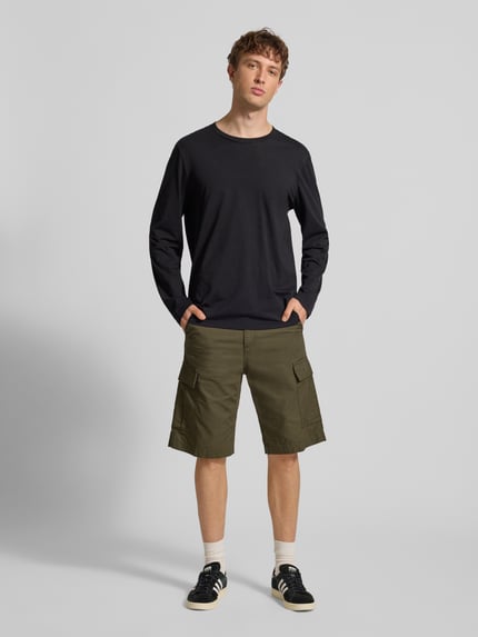 Męski model nosi Shorts mit Cargotaschen von Carhartt Work In Progress w kolorze oliwkowym, krój regular fit, szerokość w rozmiarze 32: 43 cm, długość nogawki wewnętrznej 29 cm, z przodu, pełny widok.