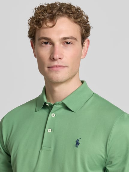 Męski model nosi Tailored Fit Poloshirt mit Label-Stitching von Ralph Lauren z mieszanki bawełny, listwa guzikowa, wyhaftowane logo, zbliżenie na górną część ciała