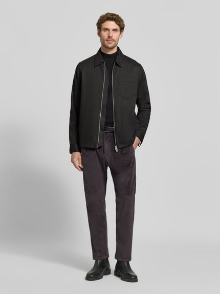 Männermodel trägt Straight Fit Hose aus Baumwoll-Mix Modell 'Chasy' von DRYKORN in Cord-Optik, dunkle Farben, Ganzkörperansicht von vorne. Elastischer Stoff, Gesäßtaschen, Knopf- und Reißverschluss, context: Herren Hose, Bundweite 40 cm, Innenbeinlänge 71 cm.