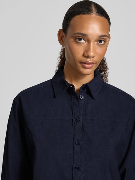 Vrouwenmodel draagt Regular Fit Bluse aus Feincord van Christian Berg Woman in donkerblauw, puur katoen, knoopsluiting, overhemdkraag, fijne corduroy structuur, detailopname bovenlichaam, ruglengte maat 36 67 cm, mouwlengte 45 cm.