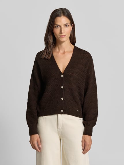 Frauenmodel trägt Strickjacke mit V-Ausschnitt und Knopfleiste von MORE & MORE, Mix mit Woll-Anteil in Dunkelbraun, Regular Fit, Ganzkörperansicht von vorne.