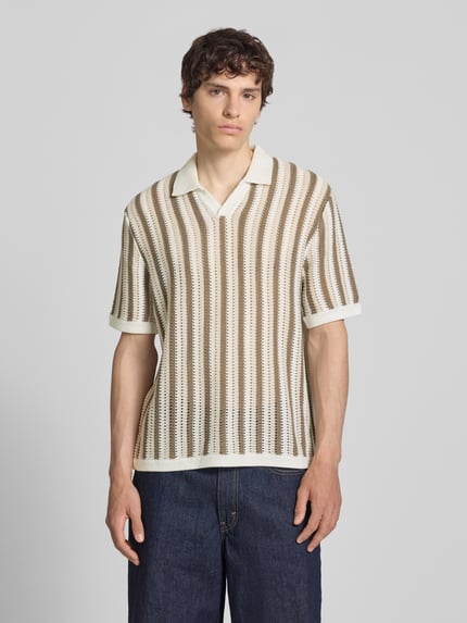 Männermodel trägt Regular Fit Poloshirt aus Baumwoll-Mix Modell 'THUE' von Only & Sons mit gestreiftem Lochstrickmuster, V-Ausschnitt, kurzarm, Struktur in Beige und Weiß, Ganzkörperansicht von vorne.