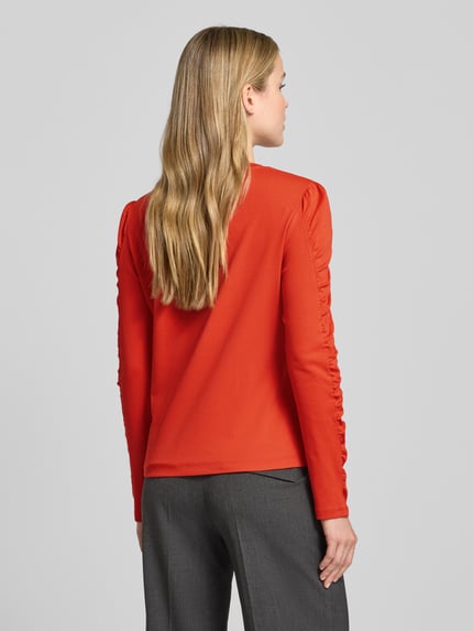 Modelka kobieca nosi longsleeve z bufkami i okrągłym dekoltem od Marc Cain, kolor czerwony, mieszanka bawełny z elastanem, regular fit, widok całej sylwetki z tyłu.