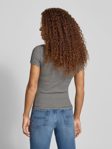 Modelka kobieca nosi Slim Fit T-Shirt aus Baumwoll-Mix od Tommy Jeans, szare, prążkowany materiał, logo, krótki rękaw, widok całej sylwetki z tyłu.