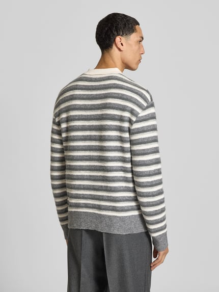 Männermodel trägt Poloshirt mit kurzer Knopfleiste von Officine Générale, mehrfarbig gestreift, Strickoptik, Ganzkörperansicht Rückansicht.