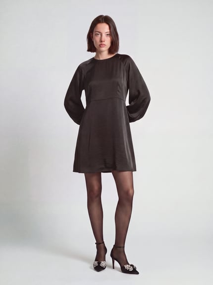Frauenmodel trägt Minikleid mit Satinoptik von VERO MODA in Unifarbe, Rundhalsausschnitt, Ballonärmeln und ausgestelltem Saum, Ganzkörperansicht von vorne.