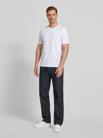 Männermodel trägt T-Shirt mit Label-Detail von bugatti in Weiß, reine Baumwolle, gerader Schnitt, Rundhalsausschnitt, Ganzkörperansicht von vorne.