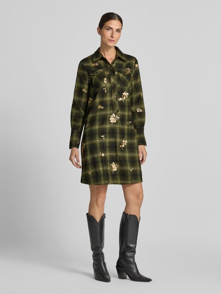 Frauenmodel trägt knielanges Hemdblusenkleid mit Pailletten Modell 'MARTERA' von 0039 Italy, kariert, grün-gold, Nahaufnahme Ganzkörperansicht von vorne. Material-Mix mit Viskose, gerader Schnitt, Hemdblusenkragen, Knopfleiste, Brusttaschen, Allover-Look.