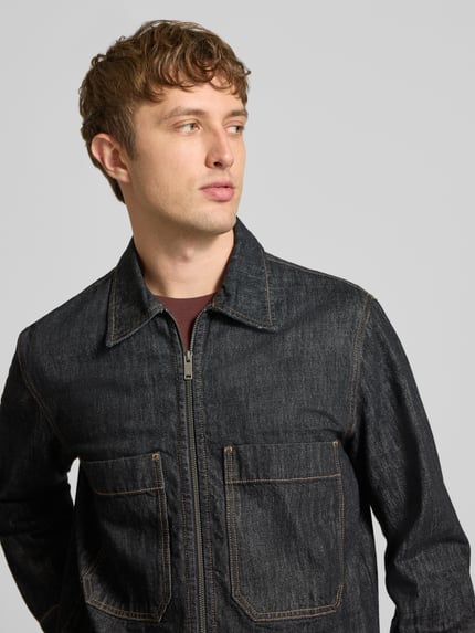 Männermodel trägt Jeansjacke mit Zweiwege Reißverschluss von ONLY, dunkles Denim mit Struktur, Brusttaschen, Nahaufnahme Oberkörper.
