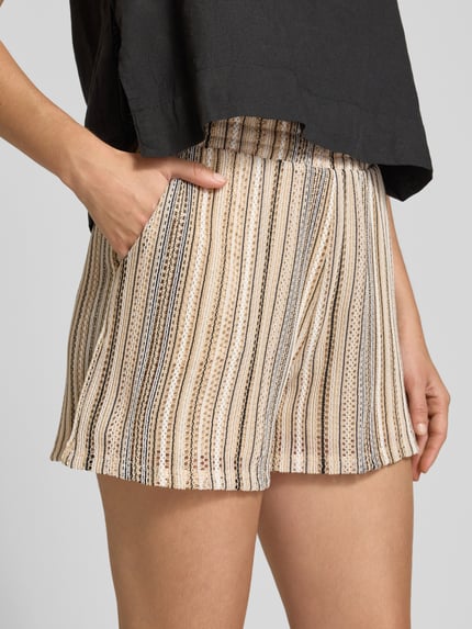 Vrouwenmodel draagt Regular Fit Shorts uit knitwear model 'DEMI' van Vero Moda, look: all-over motief, gestreept, ajourpatroon, elastische boord, zij-steekzakken, materiaalverwerking: knitwear, detailopname heup en bovenbeen.