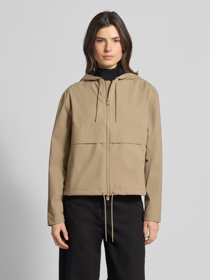 Frauenmodel trägt Regular Fit Jacke mit Kapuze Modell 'Suva' von Rains in Beige mit Zweiwege-Reißverschluss, Tunnelzug im Bund, Ganzkörperansicht von vorne. Rückenlänge 59 cm, Schulterbreite 49 cm, Brustweite 54 cm, Ärmellänge 60 cm bei Größe S.