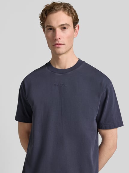 Männermodel trägt Relaxed Fit T-Shirt aus reiner Baumwolle von Marc O'Polo, Optik: Unifarben, Label-Schriftzug, Nahaufnahme Oberkörper.